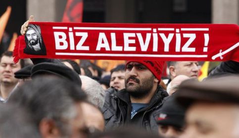 A protester holds a banner reading "we are alevi" as he and many others wait to hear the decision of the court in front of a courthouse in Ankara