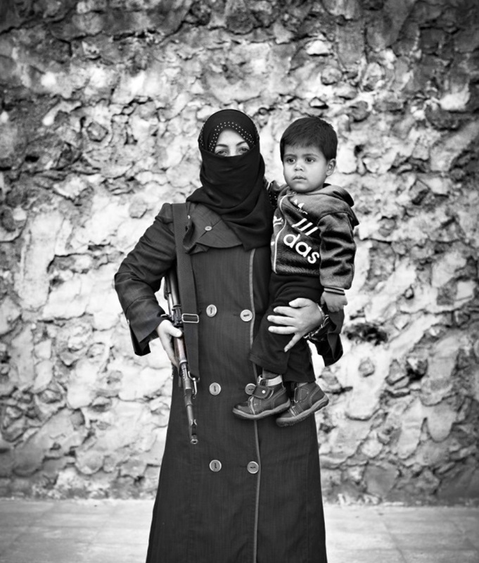فضل صورة عام 2023 سورية تحمل طفلها و سلاح الكلاشنكوف